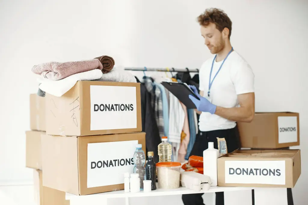 Volunteer organizing various goods for donation. Charitable cause and community support.