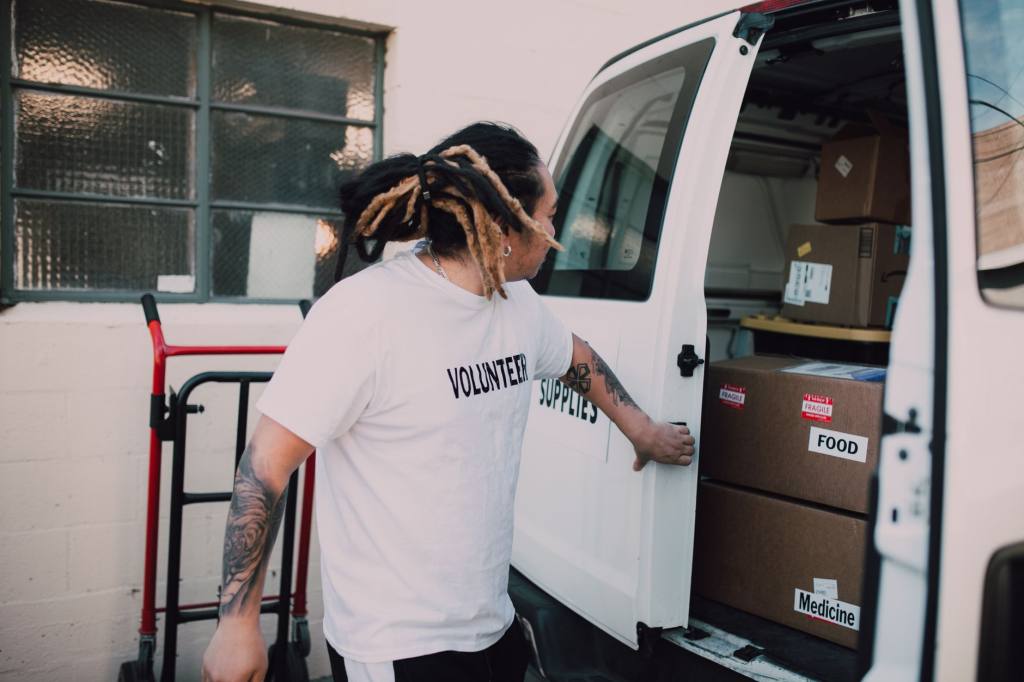 Volunteer loading boxes labeled food and medicine into van, supporting community donations.