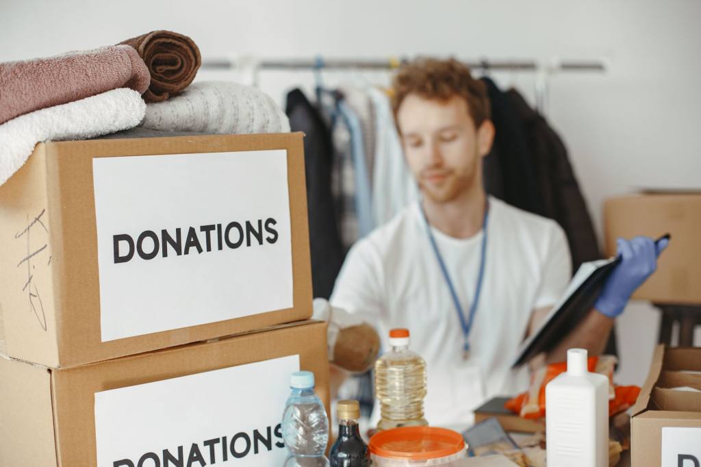 Volunteer organizing donation boxes with clothes and supplies for charity.