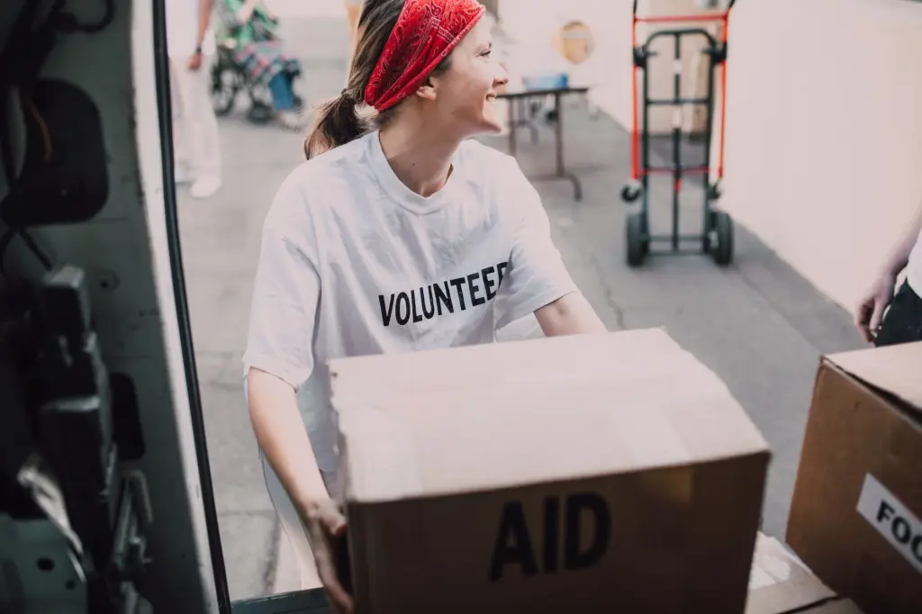 Smiling volunteer woman carrying aid boxes for a charity event.